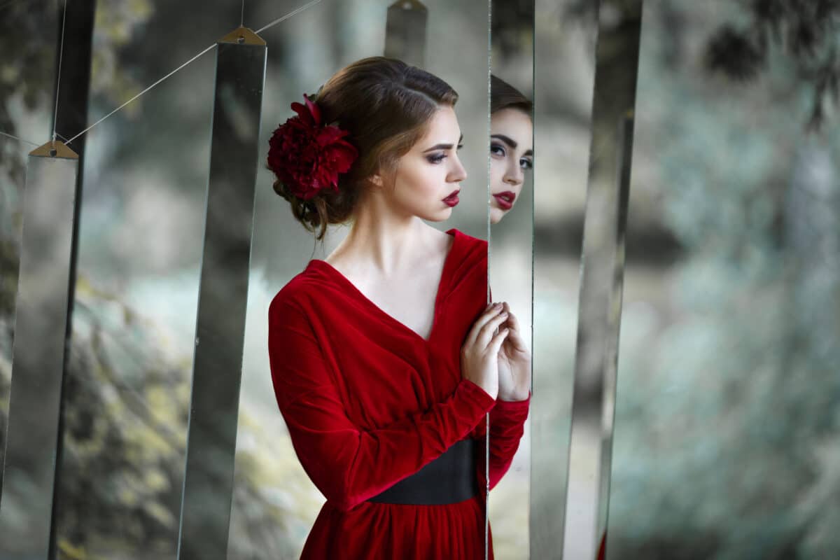 Mysterious girl in a long red dress in nature