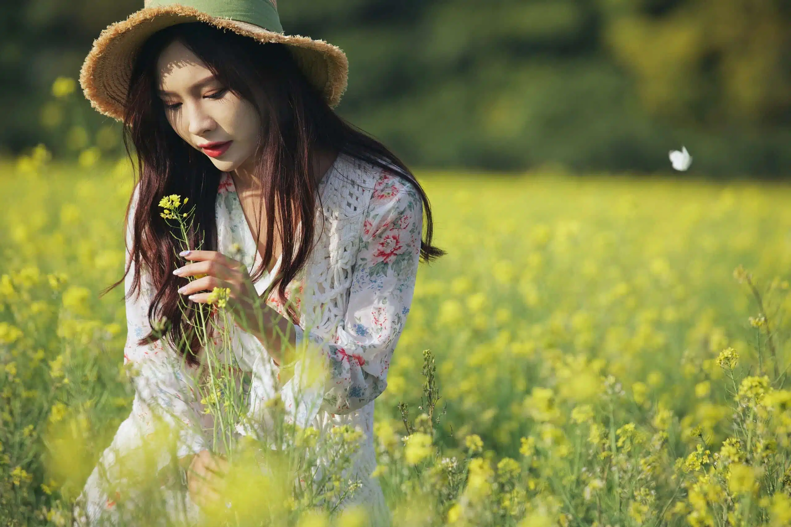 pensive Asian lady enjoying in the field of yellow flowers