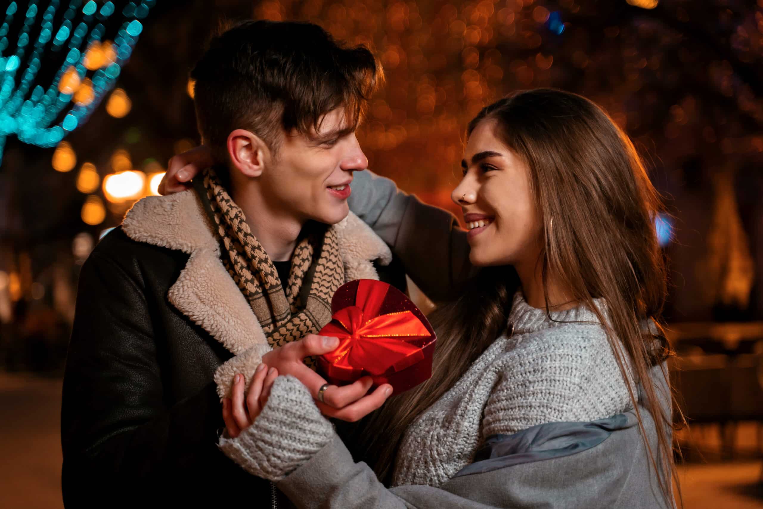 Young romantic couple on the street, man giving a present to his girlfriend