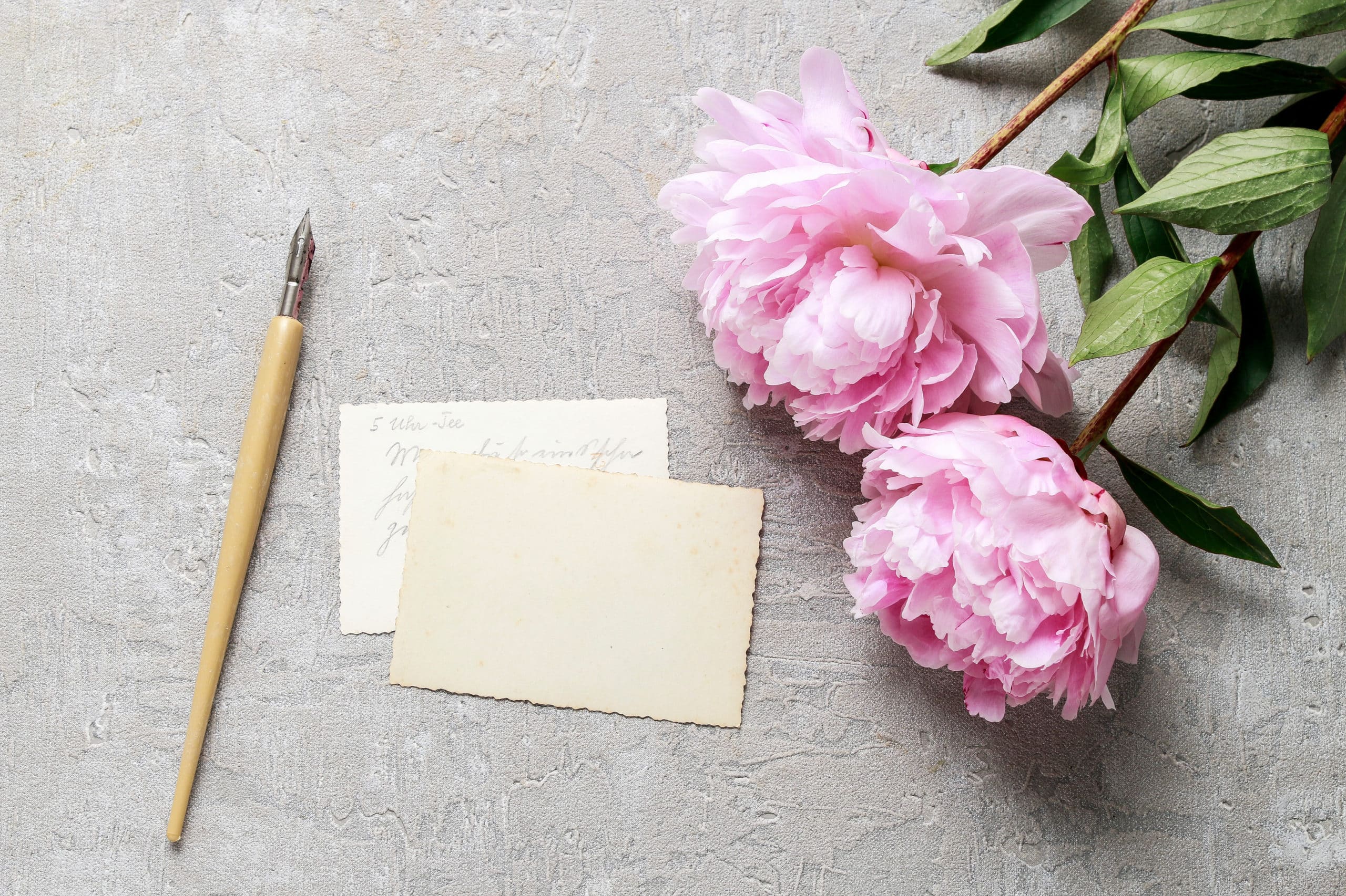 Handwritten letters and pink peonies on grey background
