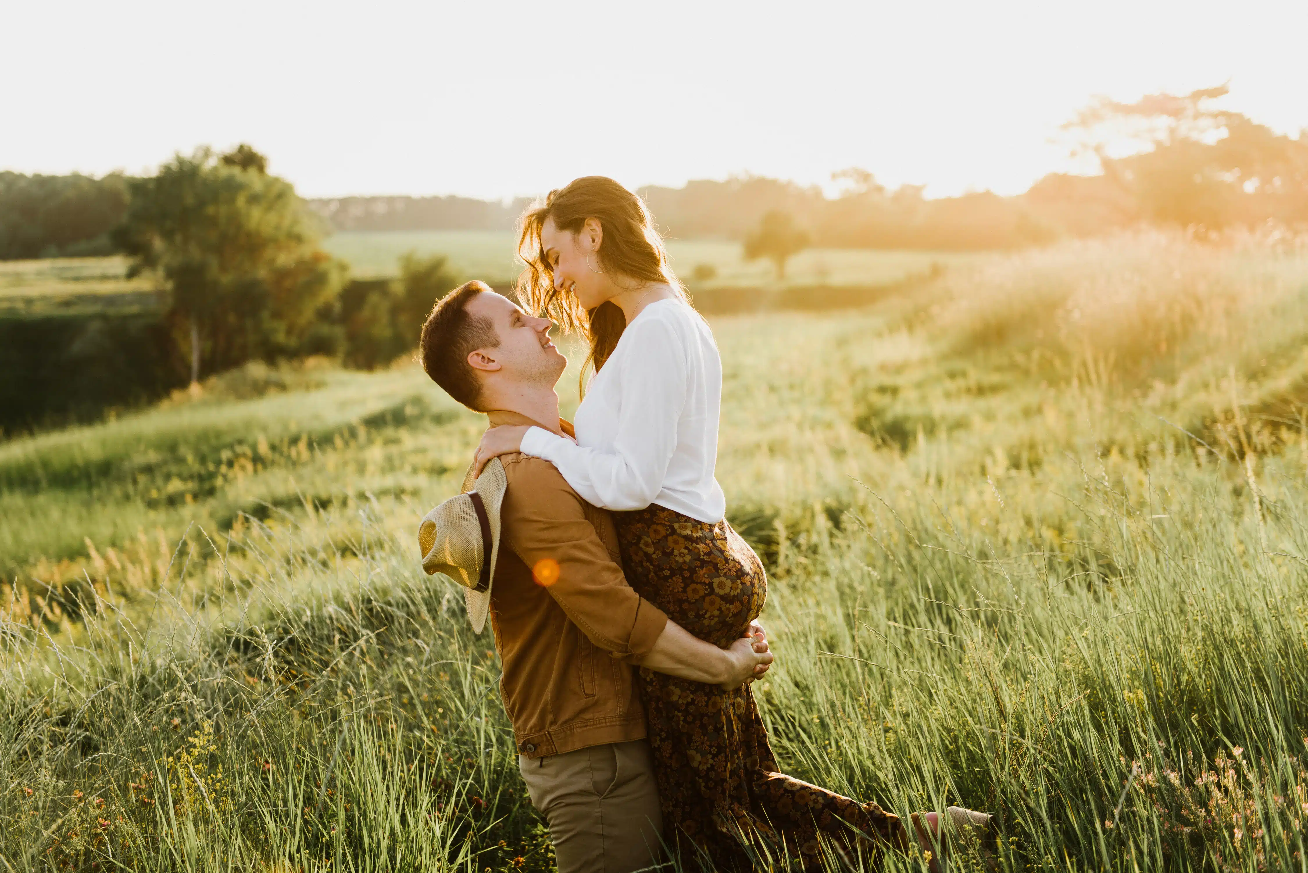 Beautiful young woman and a man walk, hug and kiss in nature at sunset.