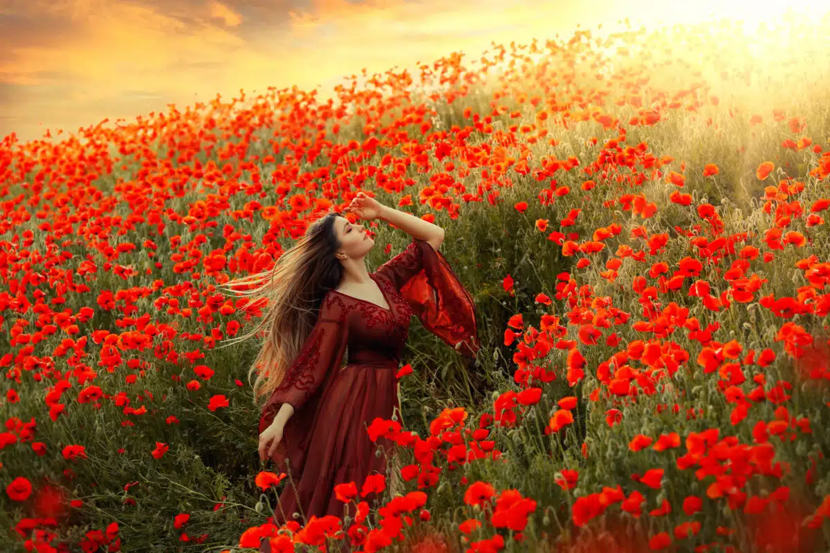 happy goddess walks in poppy field long hair flying in wind