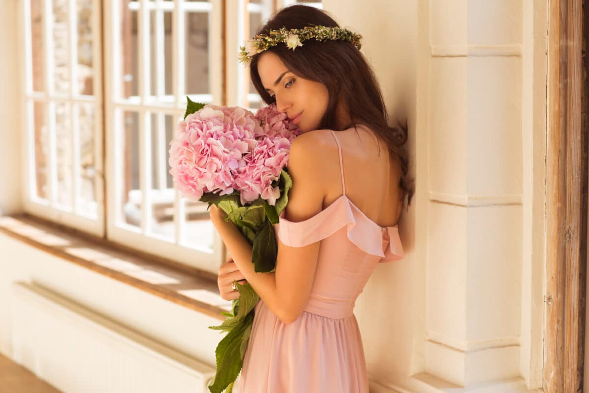 a beautiful woman holding a pink hydrangeas in her arms