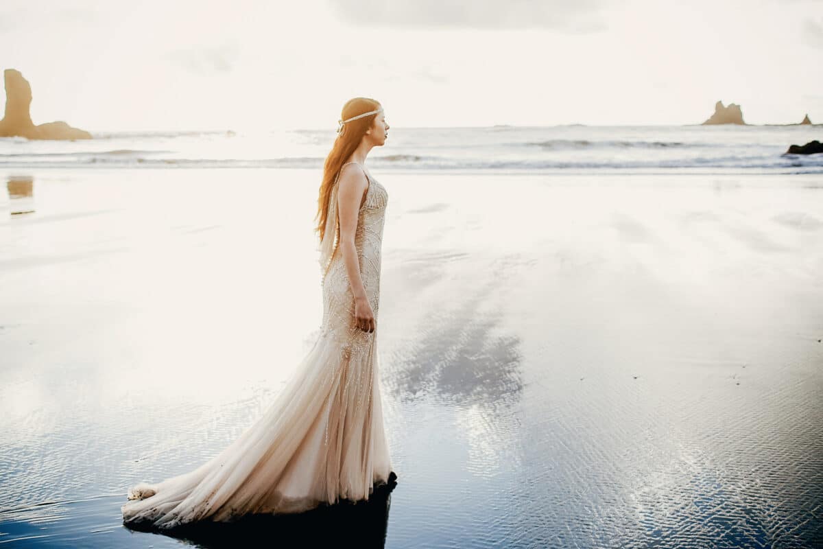 mysterious woman dressed in white walking along the icy black sand beach 