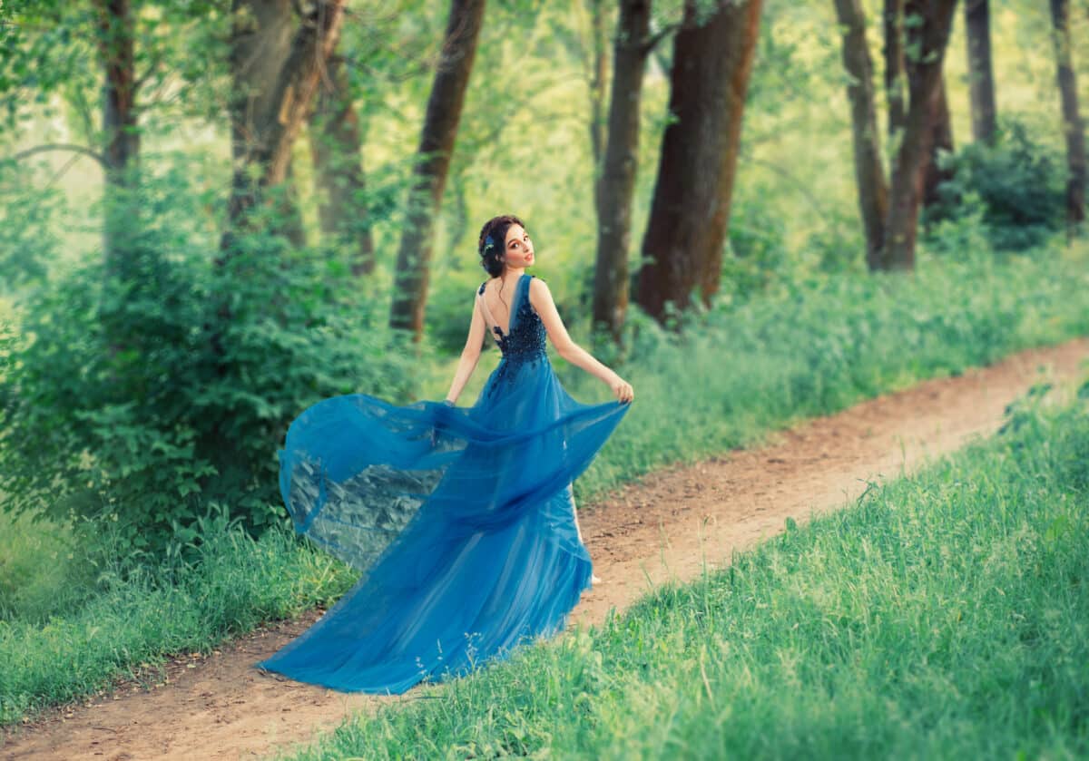 delightful gentle dancing girl, a young beautiful princess walks along secret forest paths. lady lifts the hem of an expensive royal elegant cholkovogo dress with a long train and a cut on the back.