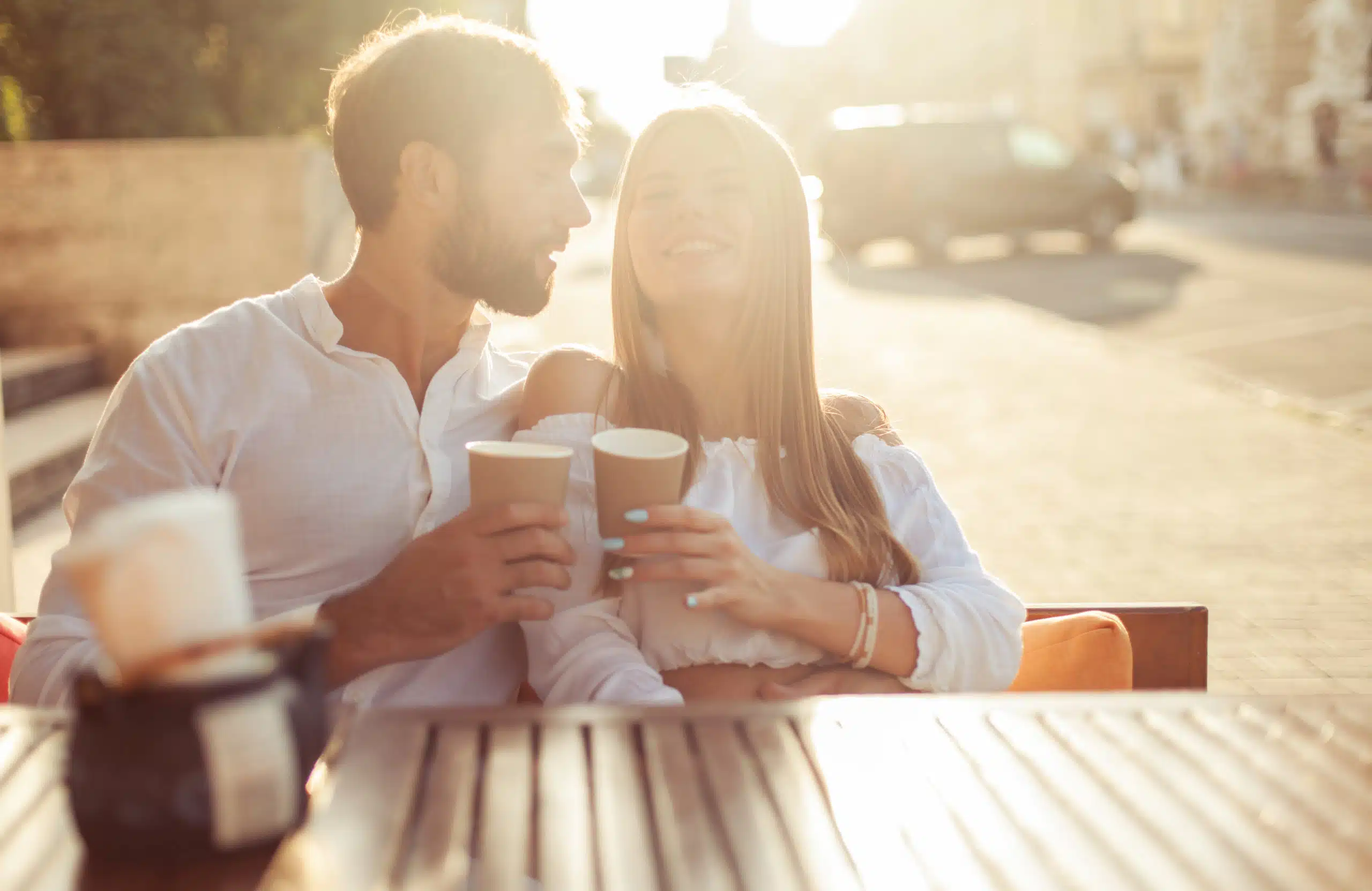 Loving couple drinking coffee in outdoor cafe at sunset