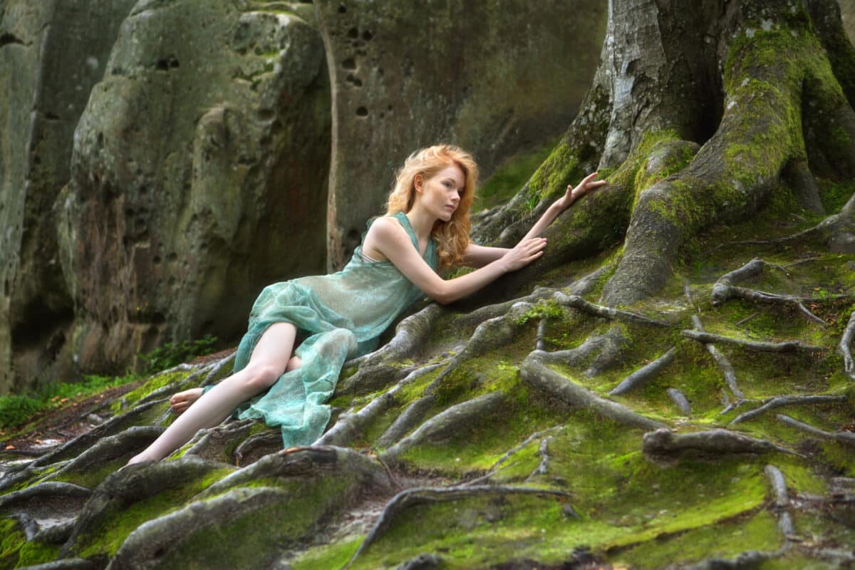 red-haired forest fairy lying on the mossy tree roots