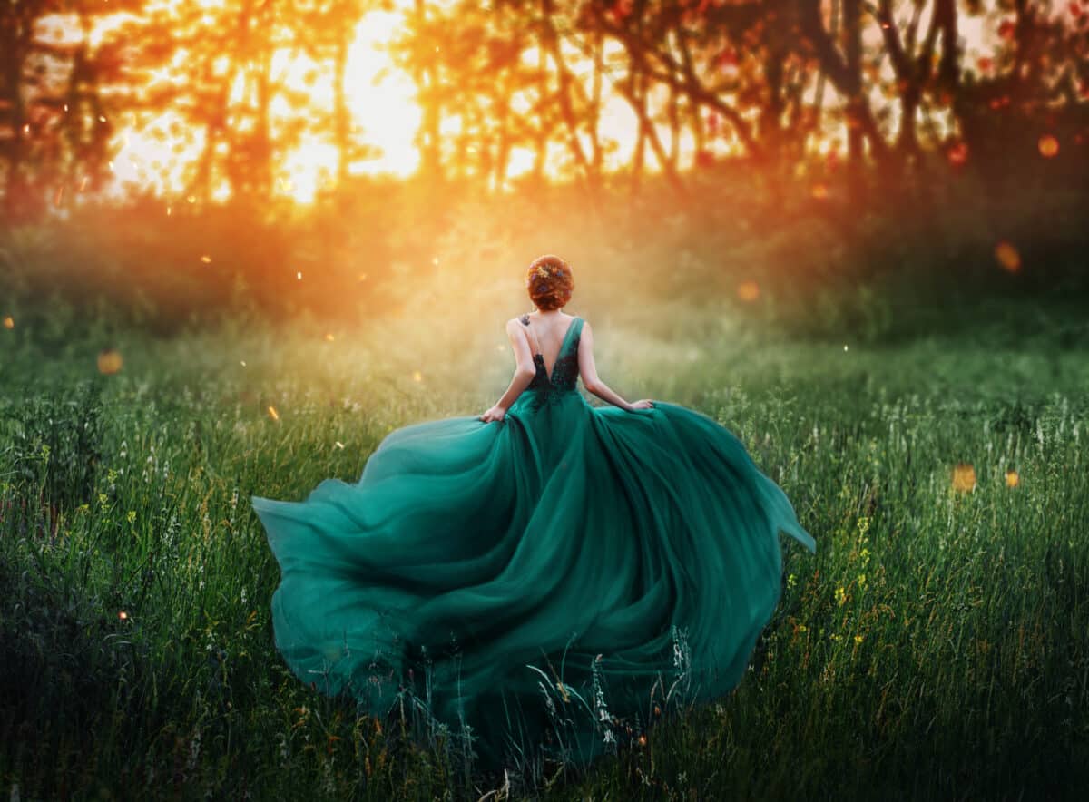 Magical picture, girl with red hair runs into dark mysterious forest, lady in long elegant royal expensive emerald green turquoise dress with flying train, amazing transformation during fiery sunset.