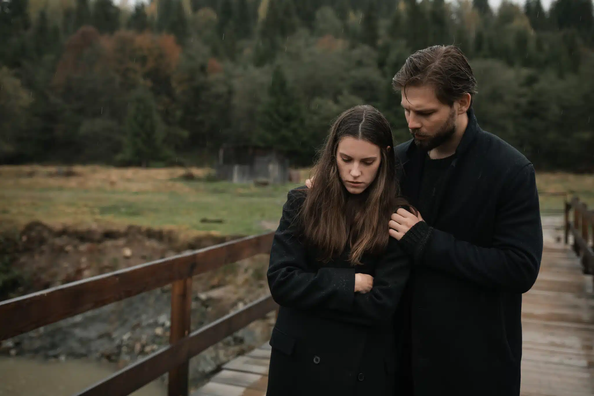 A young couple in love in black coats walks in the countryside 