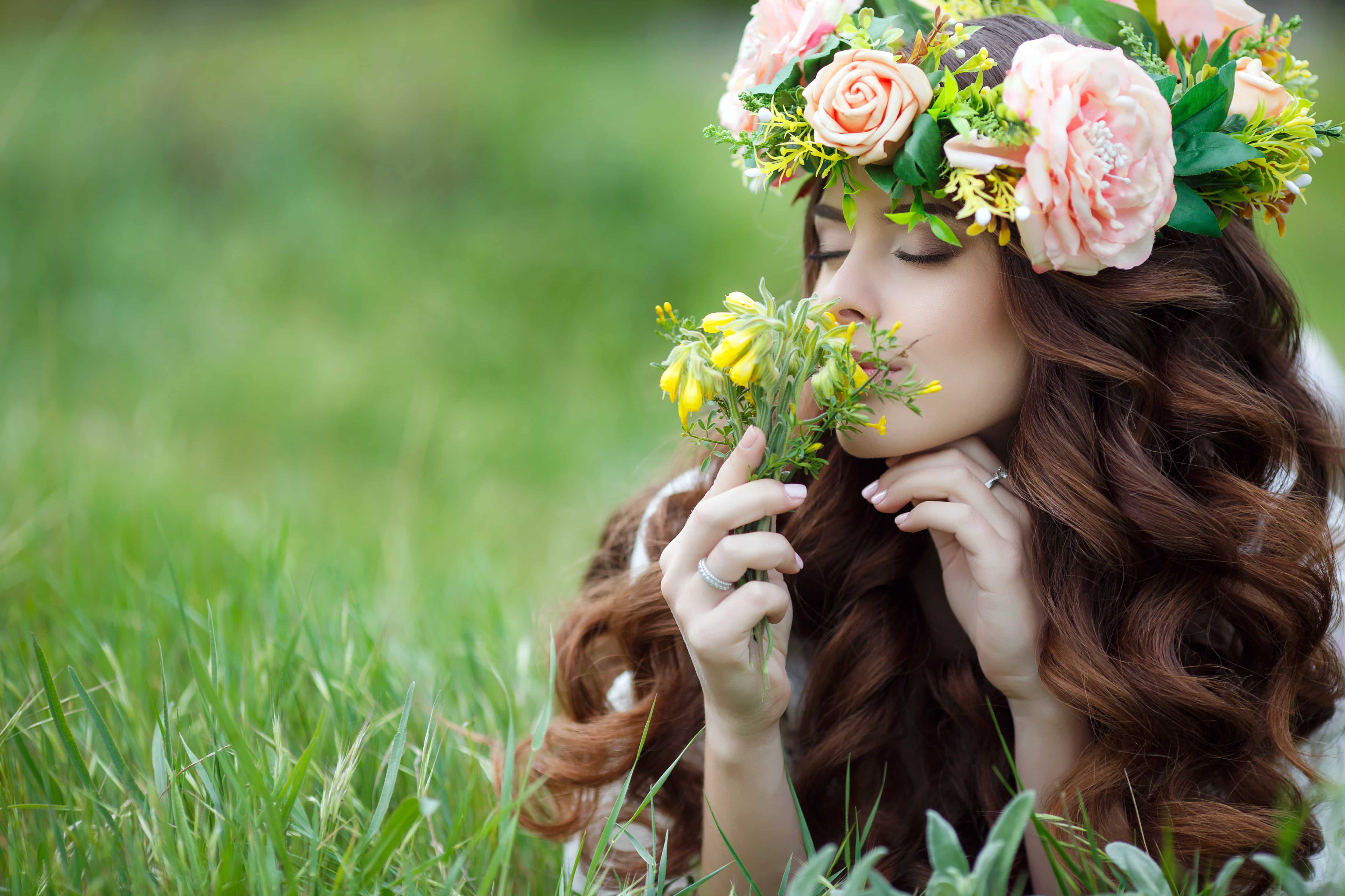 beautiful woman in wreath of spring flowers, lying on the grass