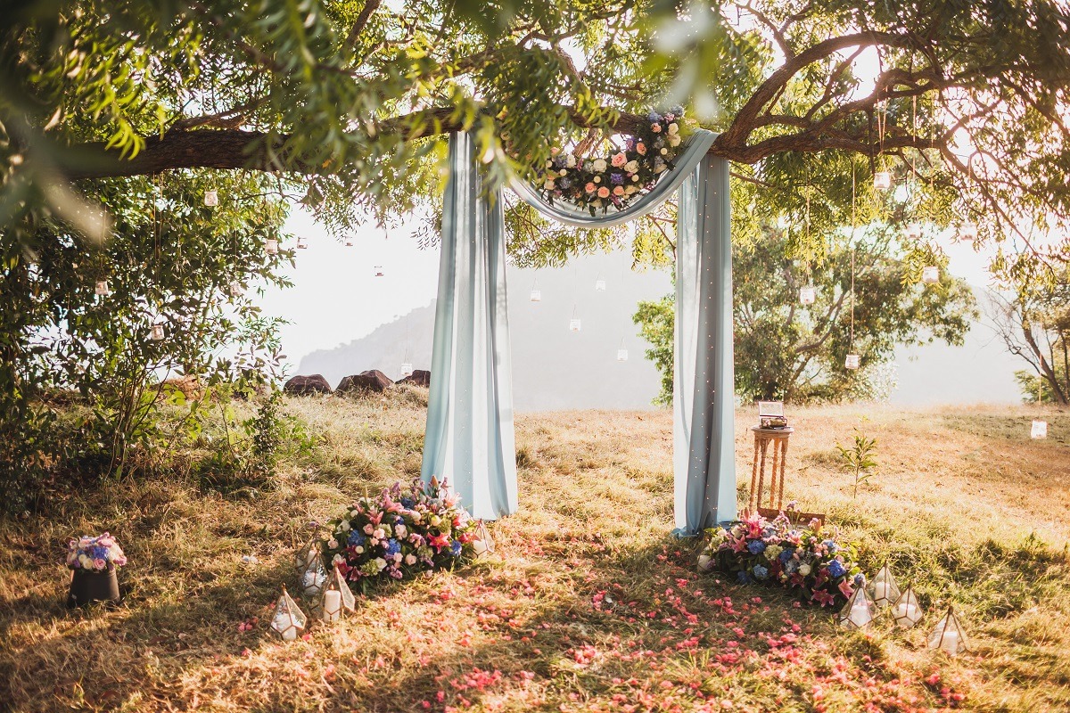 Sunset wedding ceremony, arch decorated with grey cloth hanging