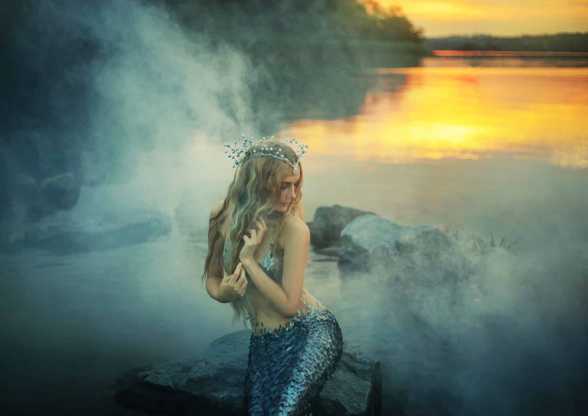 fabulous sea princess mermaid sitting on a rock in the seashore with thick fog