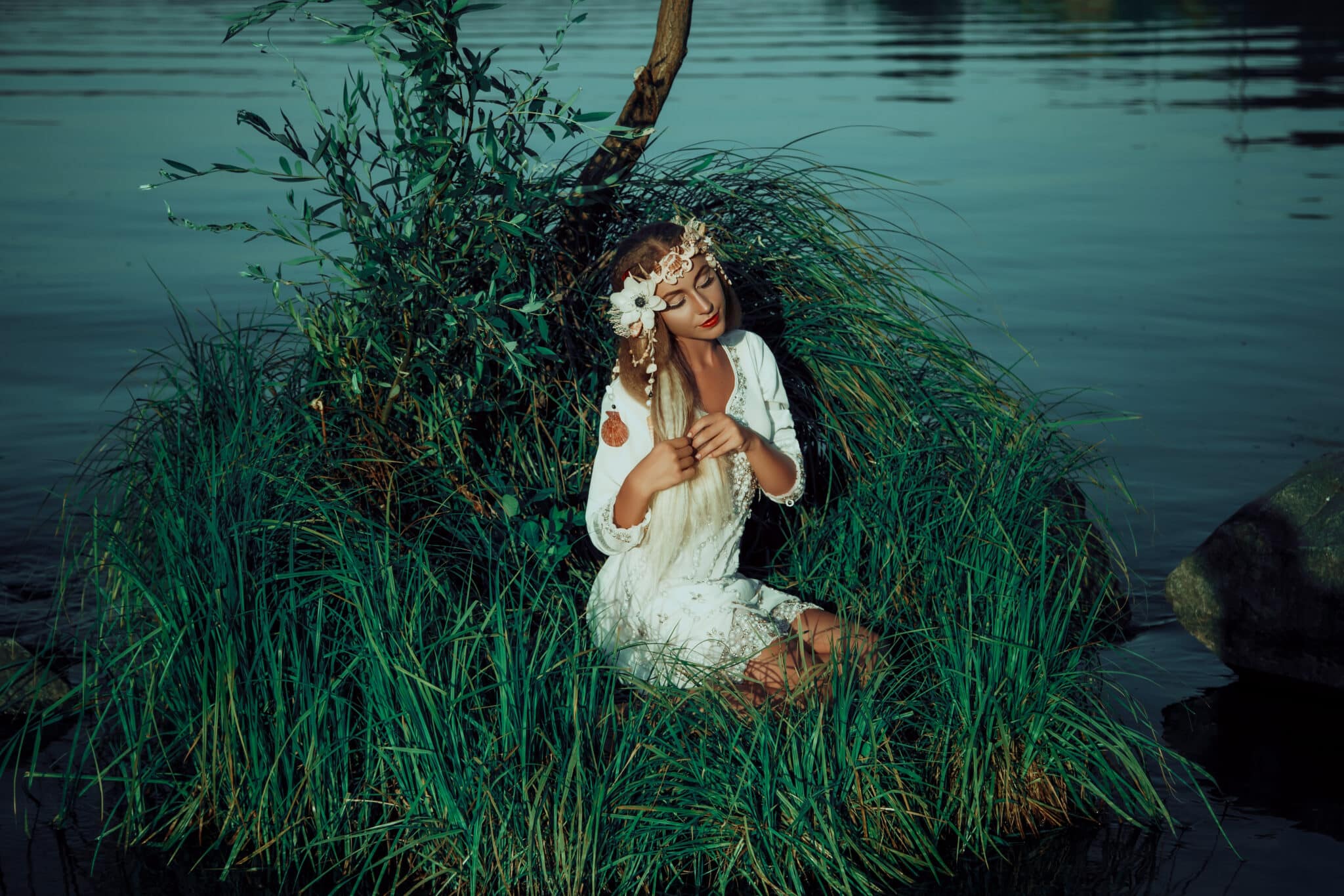 Fairy sitting on the grass in the middle of the lake. A wreath m