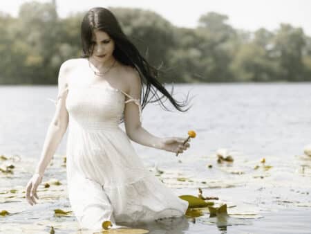 Romantic female wading in the lake with flowers