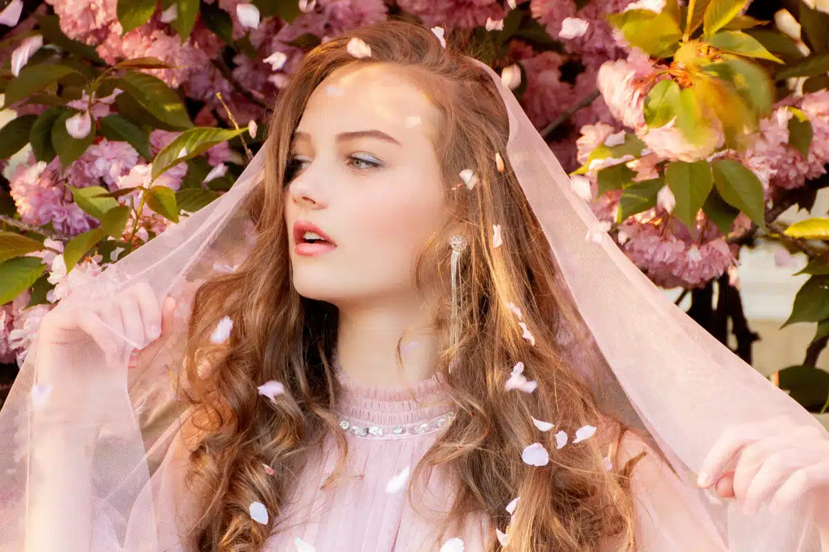 portrait of a beautiful teenager girl in delicate Sakura flowers with a veil