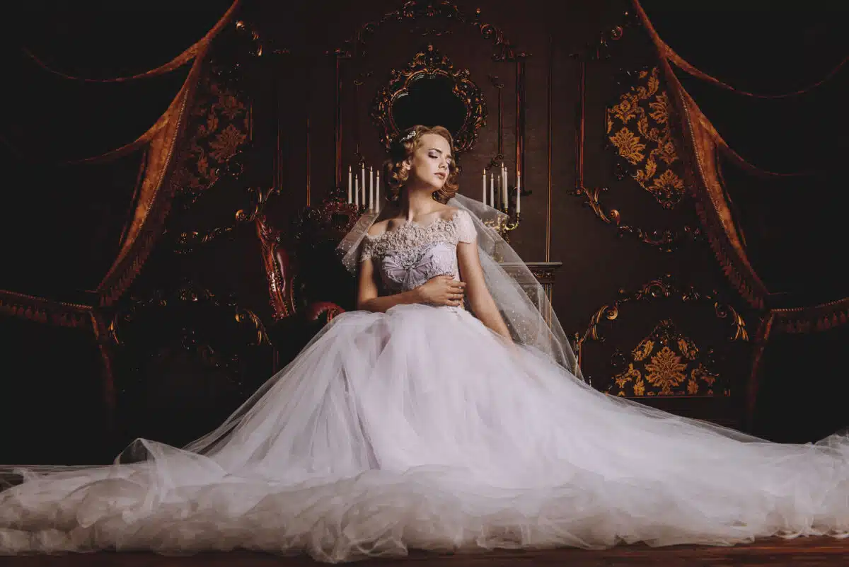 aristocratic woman in a white ball gown sitting in a luxury vintage room