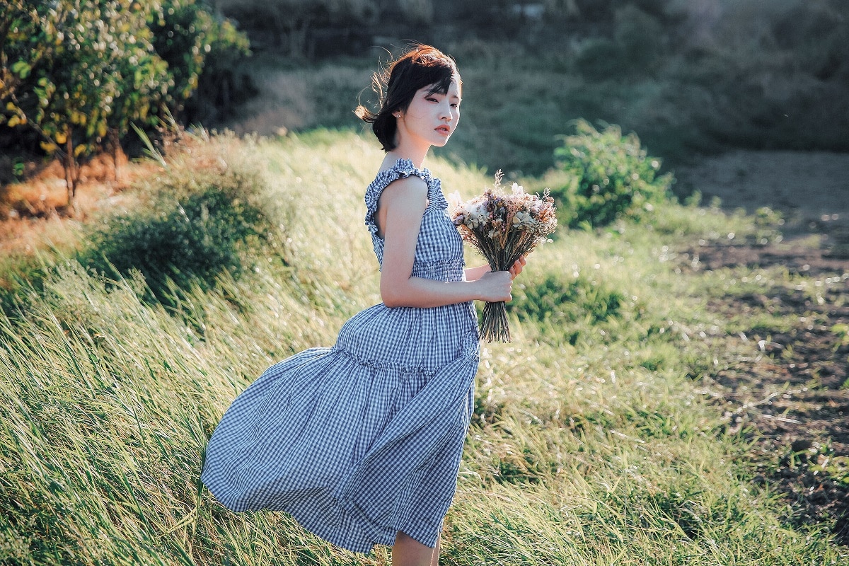 young lady holding a bouquet of wildflowers in the field