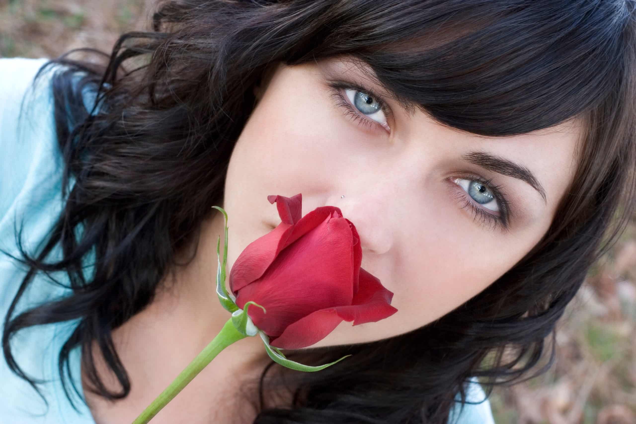 Woman with blue eyes smells rose.