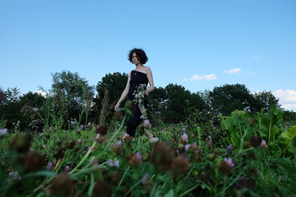 woman dressed in black in the field with wild flowers