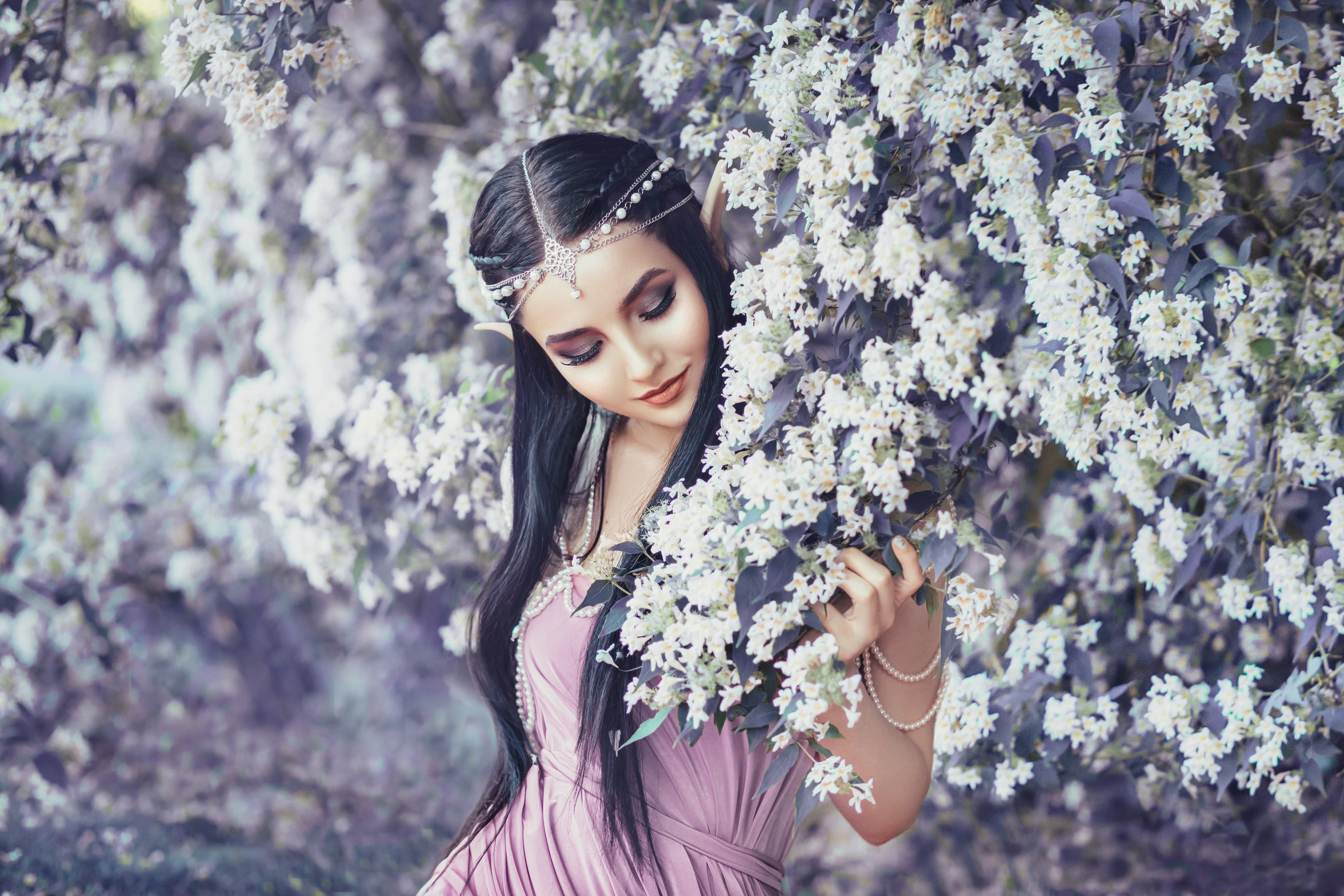 a beautiful raven haired lady standing in a blooming garden