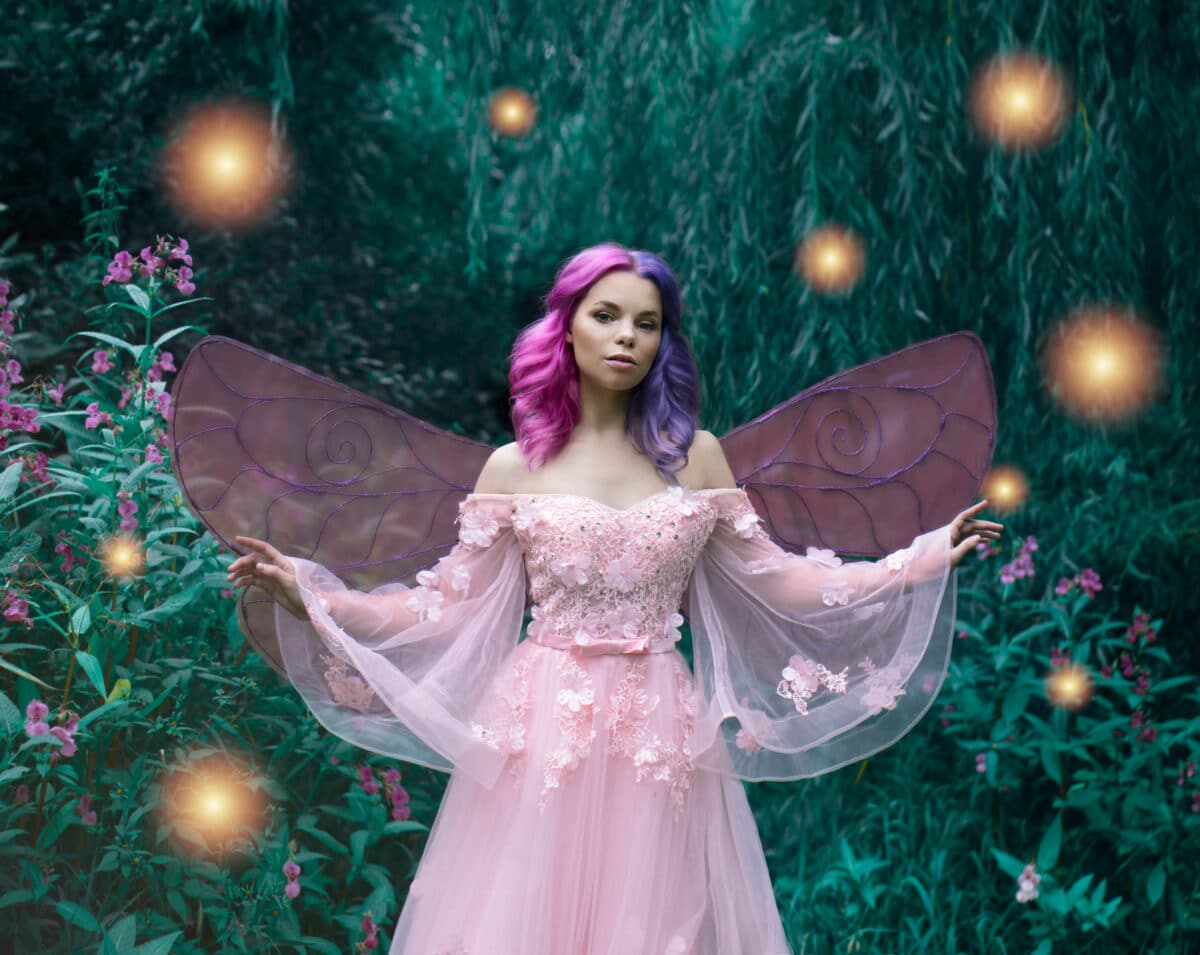 Art photo of a fairy fairy in a pink dress in the forest with fireflies closeup
