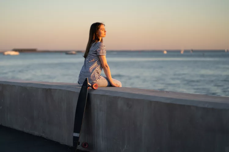 a young woman enjoys summer evening by the sea looking at the water
