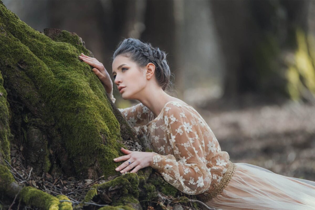 sensual young woman wearing elegant dress in a coniferous forest