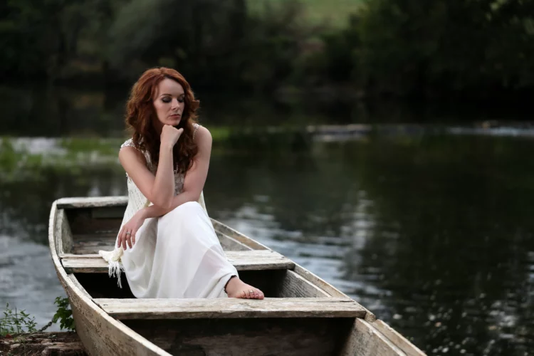 a young woman sitting on the boat docked by the lake