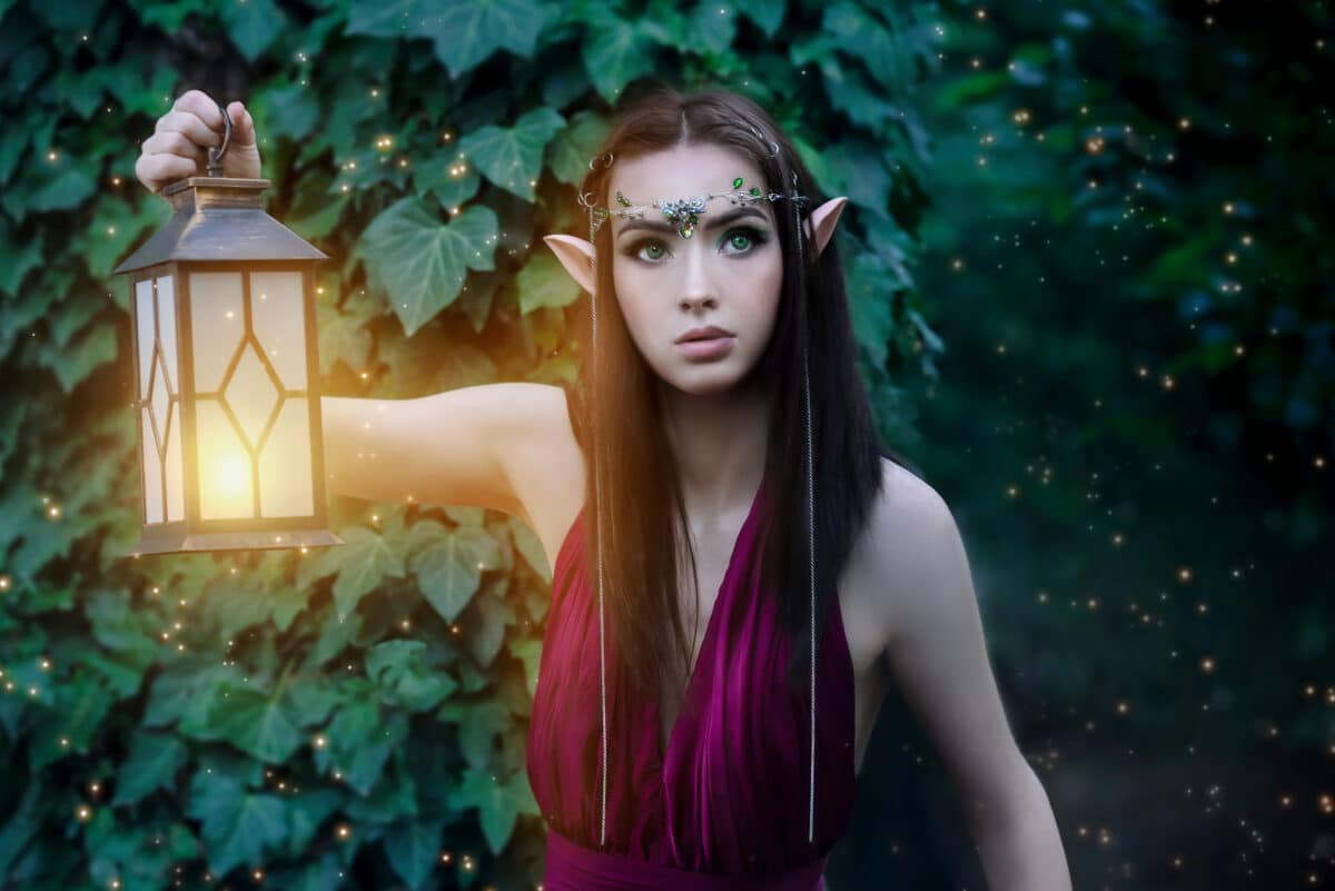 Portrait of a fabulous elven princess with a lantern in a green forest. Night in the forest.