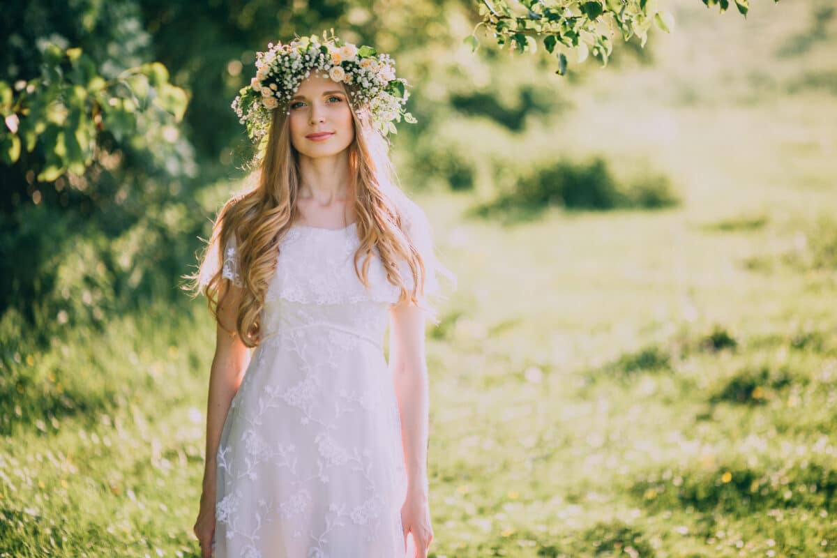 Beautiful young woman with wreath of wildflowers in their hair standing in the garden