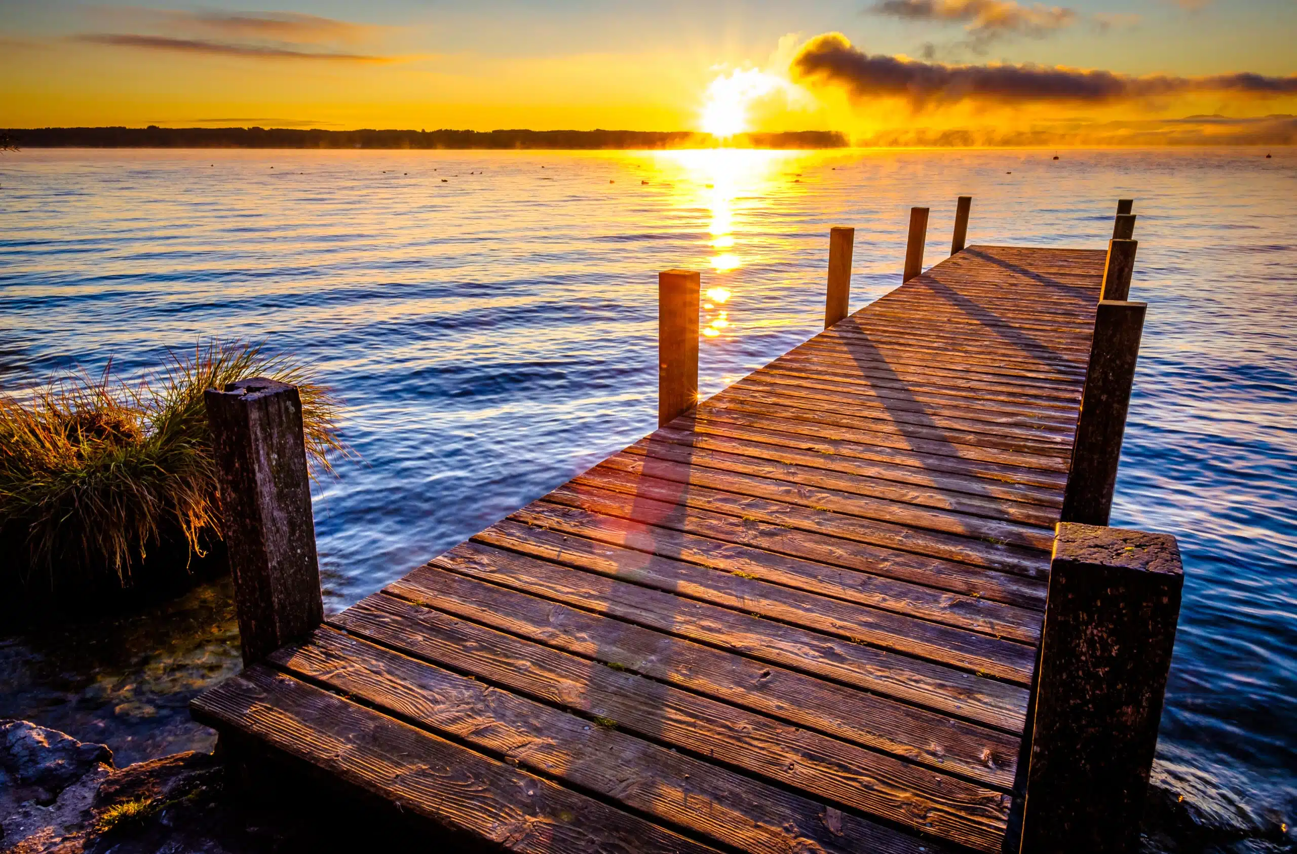Old wooden jetty at a lake at sunset.
