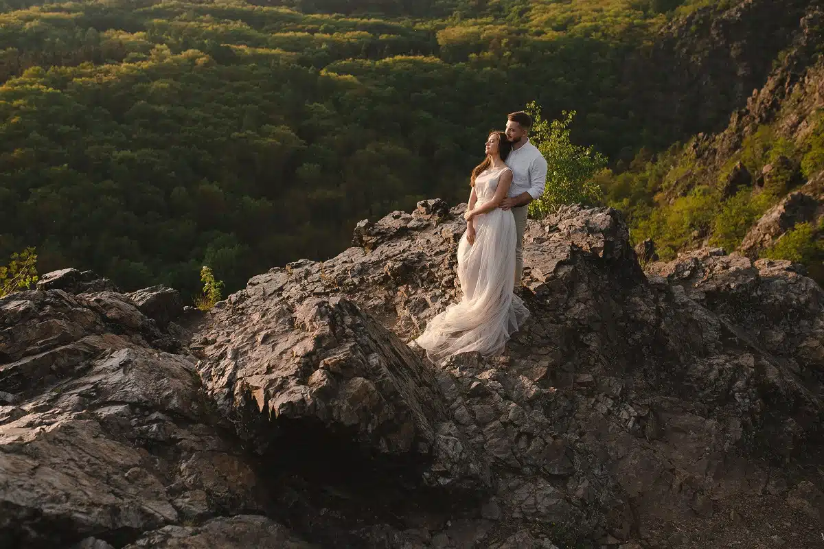 romantic couple standing on the rocks in the green mountains