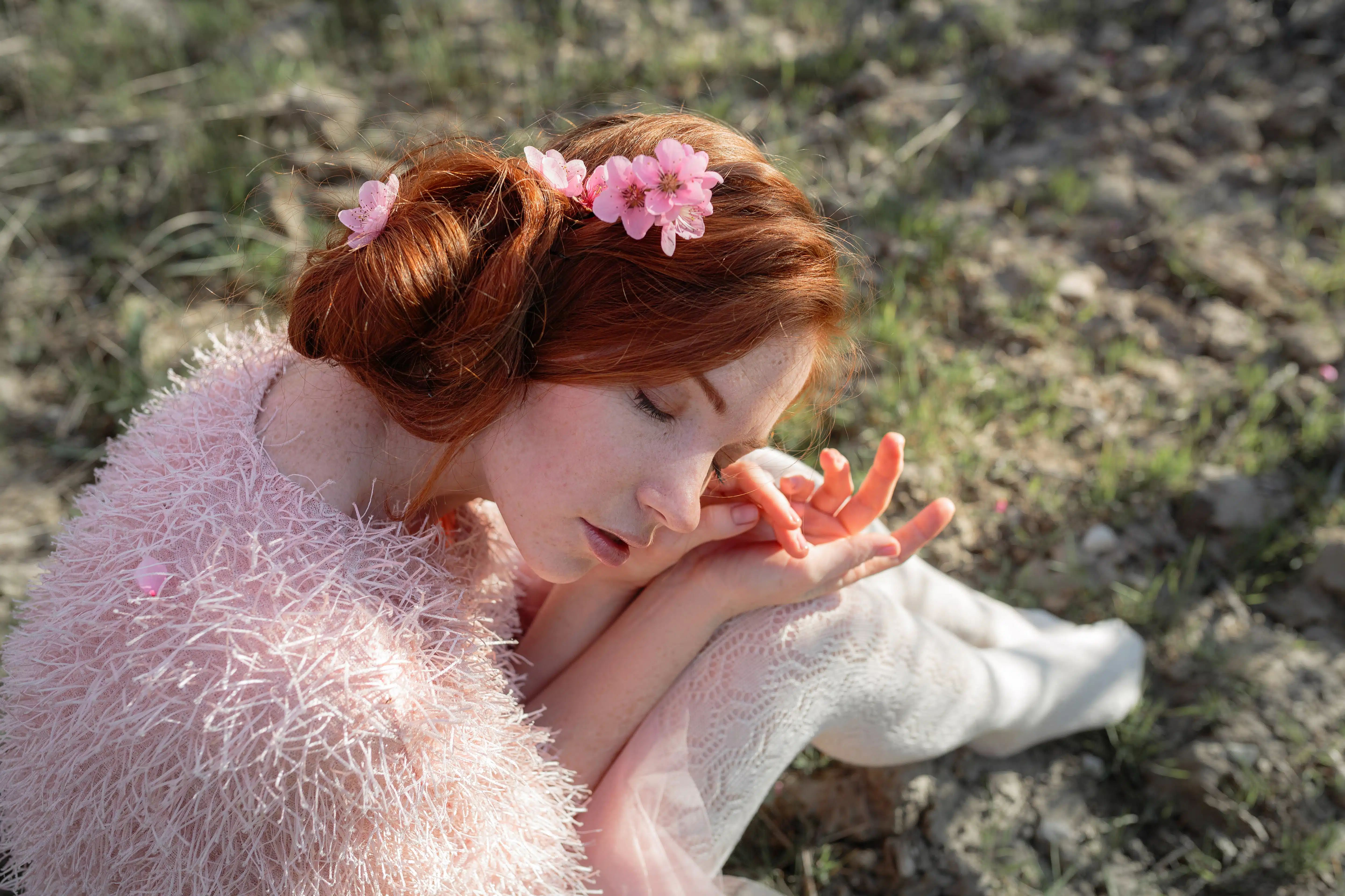 young girl with red hair in a gentle peach garden, which blossomed