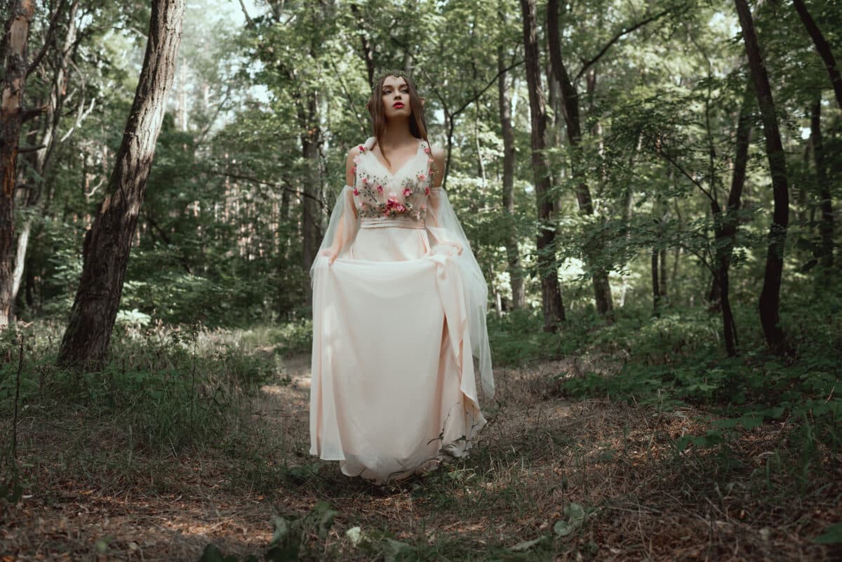mystic elf in elegant flower dress in forest
