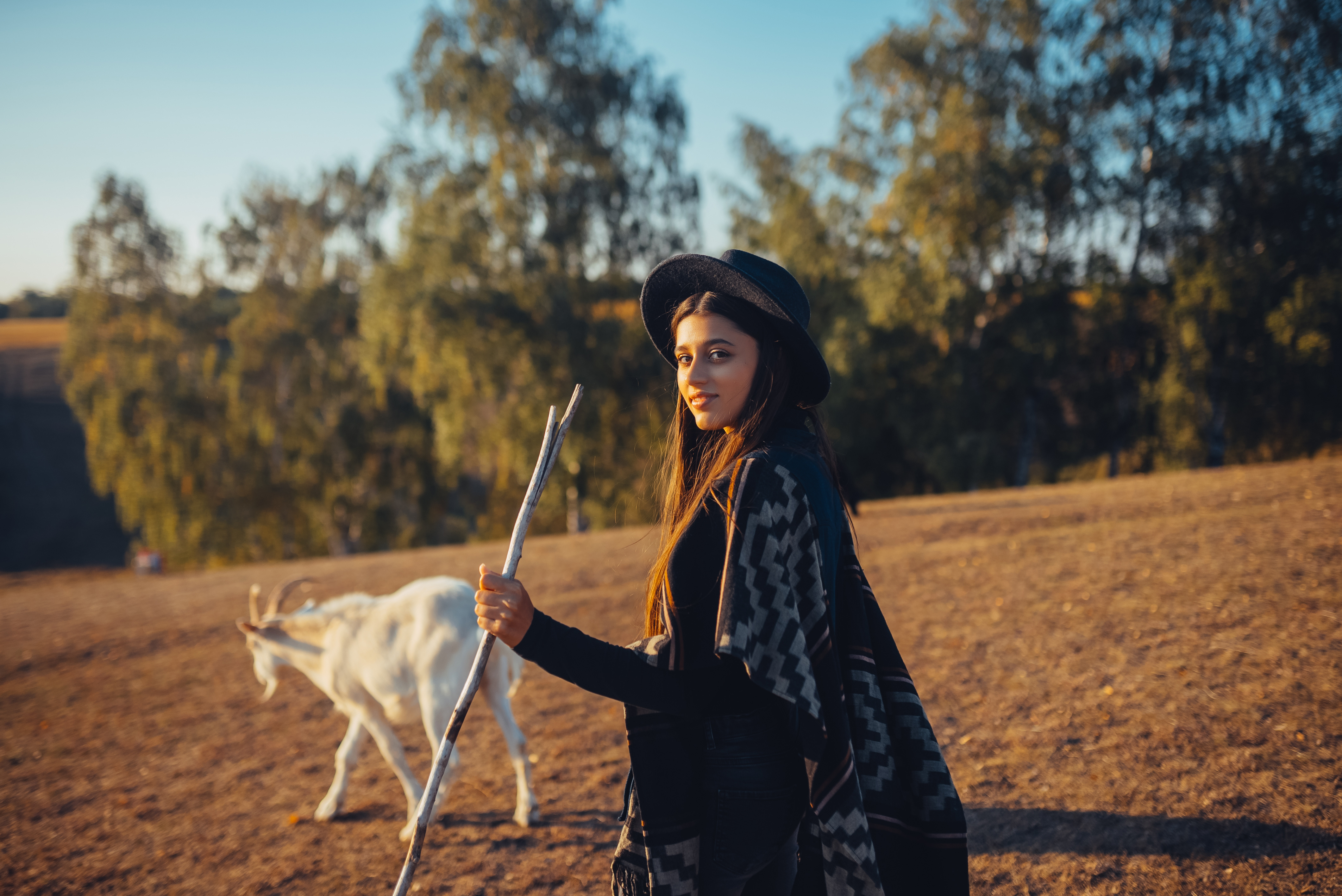 A female shepherd grazes goats on a meadow