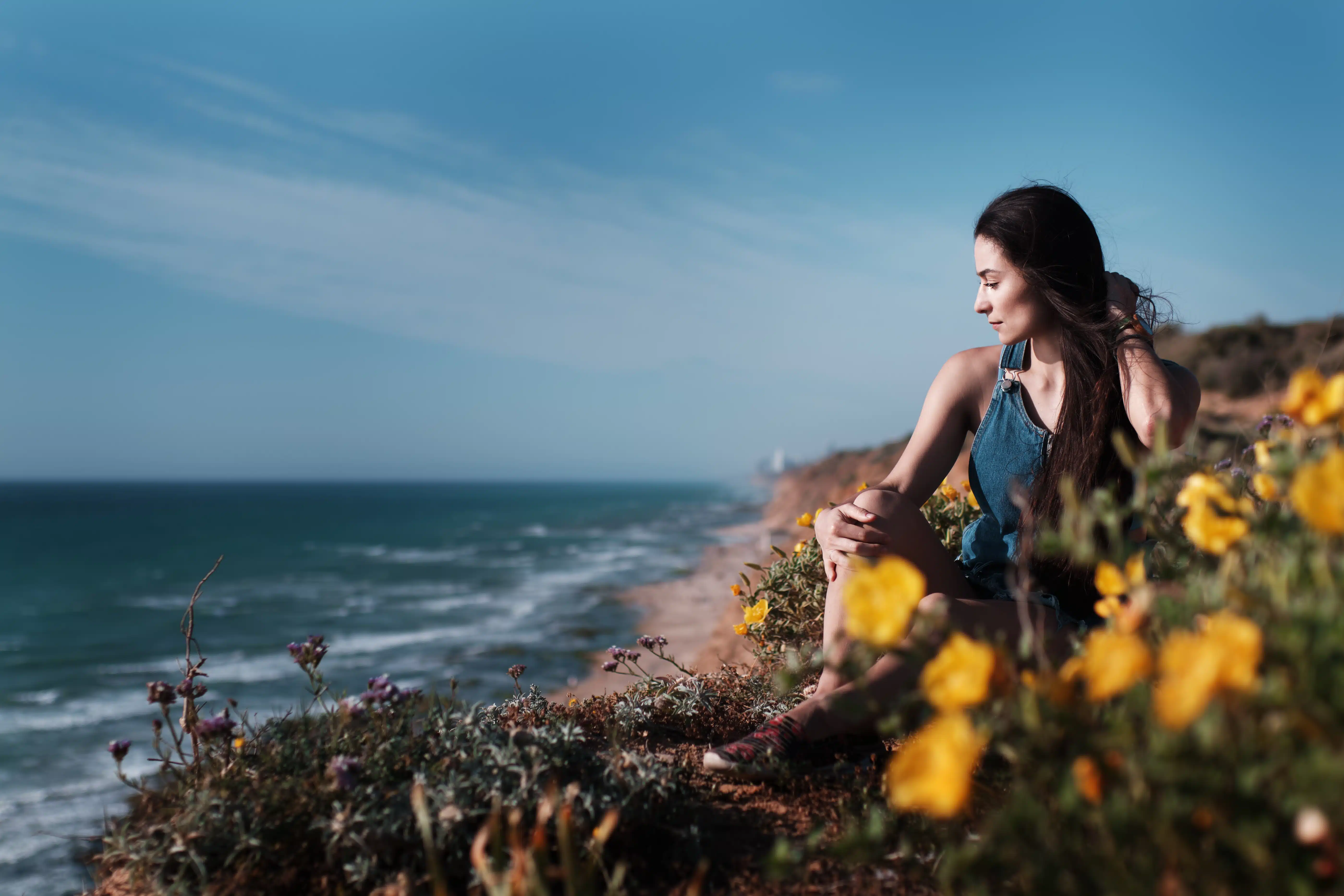 Young sad woman sitting on the edge of the cliff relaxing 