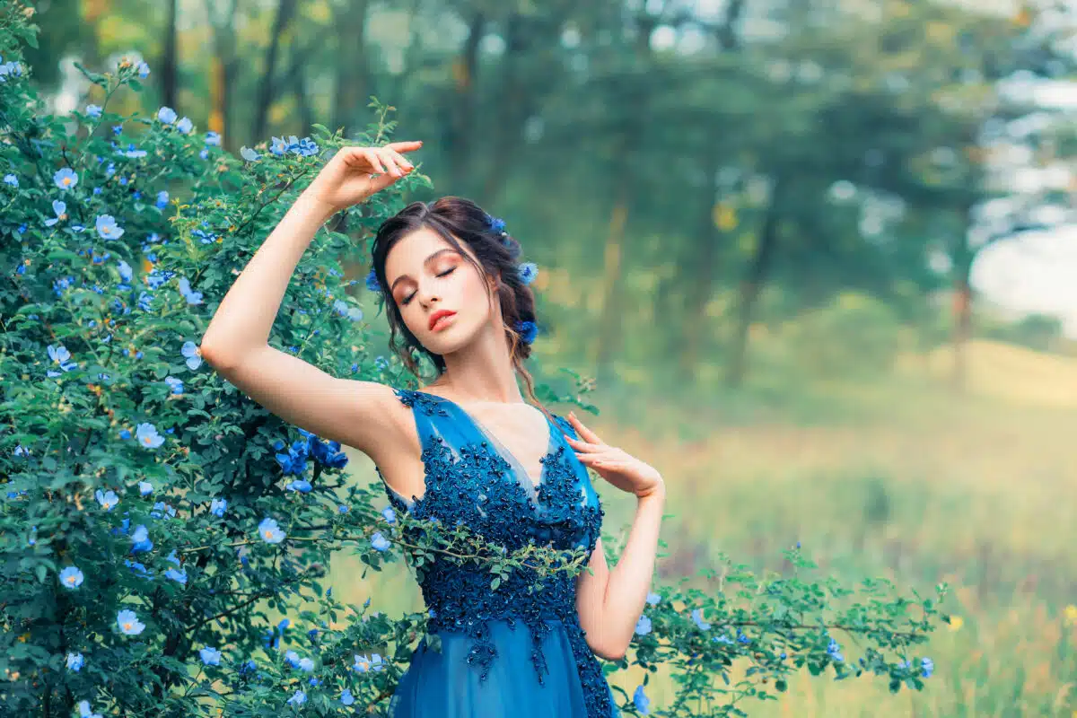 gentle nymph in a long elegant blue dress standing next to a cornflower