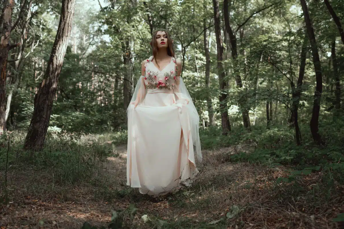 mystic elf in elegant flower dress in forest