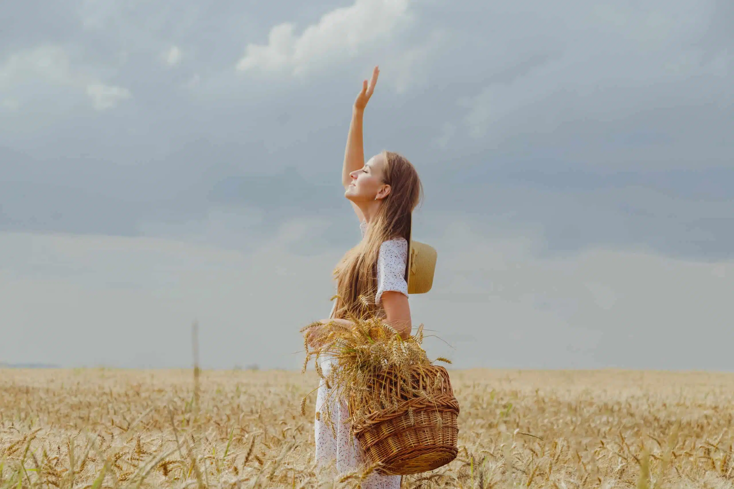 Woman in wheat field welcomes the sun. 