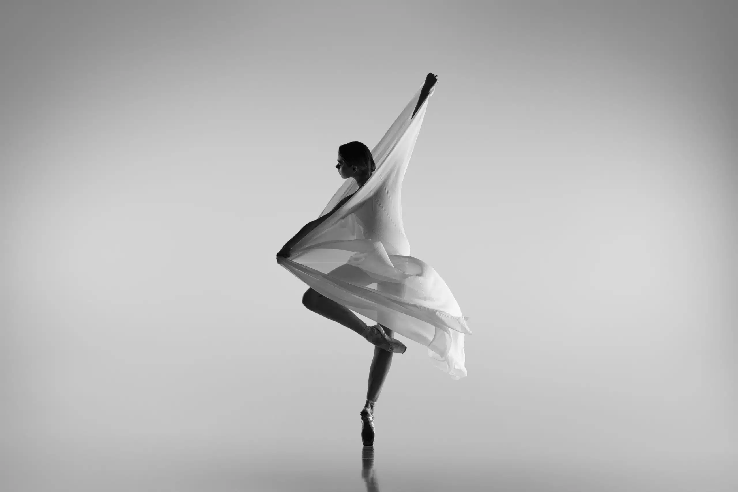 Graceful ballerina dancing with cloth depicting art isolated on grey background.