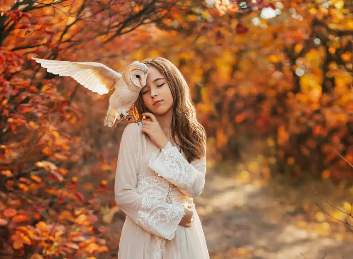 Fantasy princess enjoys nature with white barn owl on her shoulder