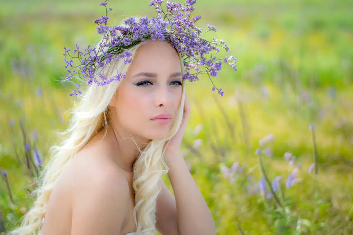 a pretty lady with purple flower head wreath is relaxing in the field