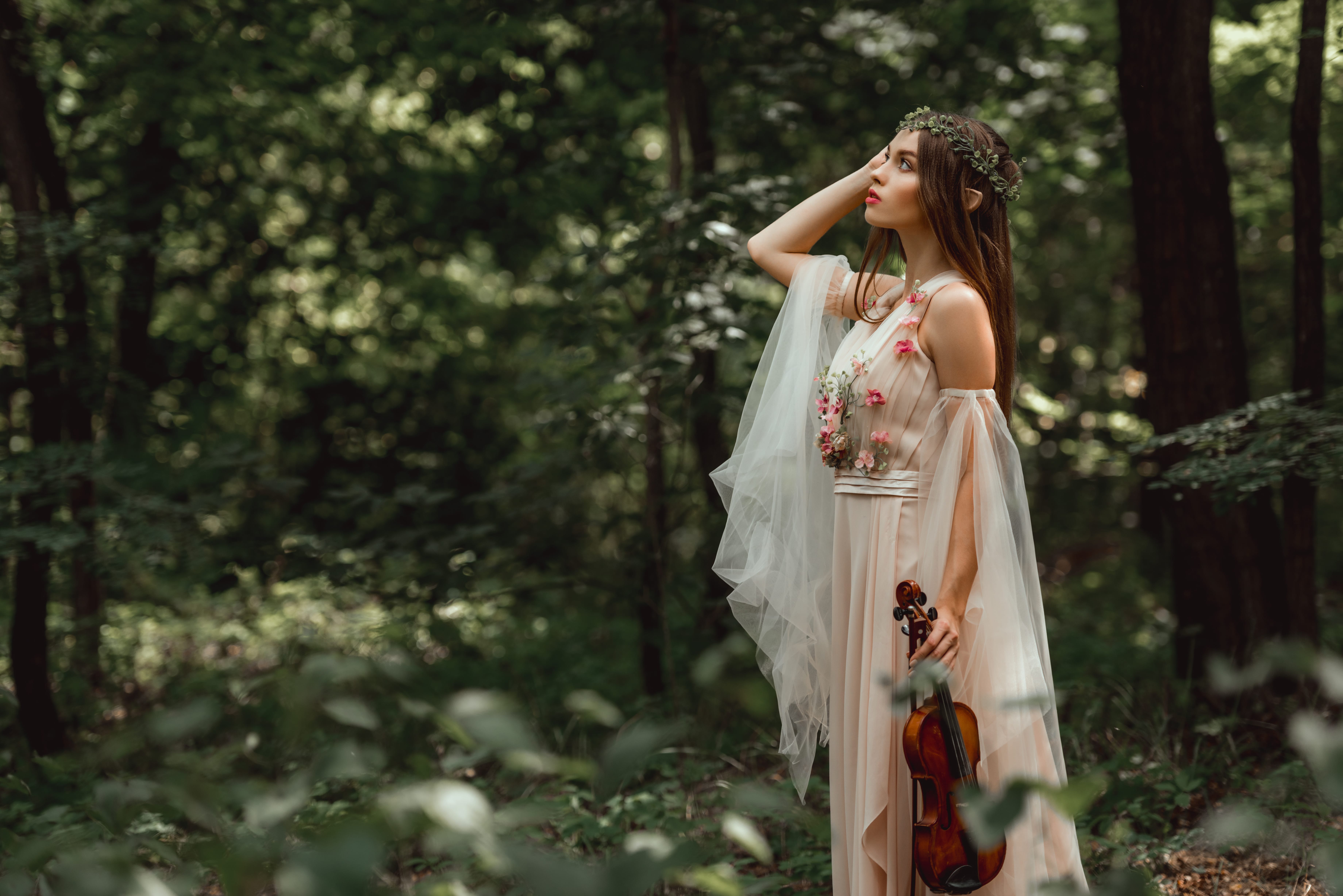 mystic fairytale character in flower dress holding violin in green forest