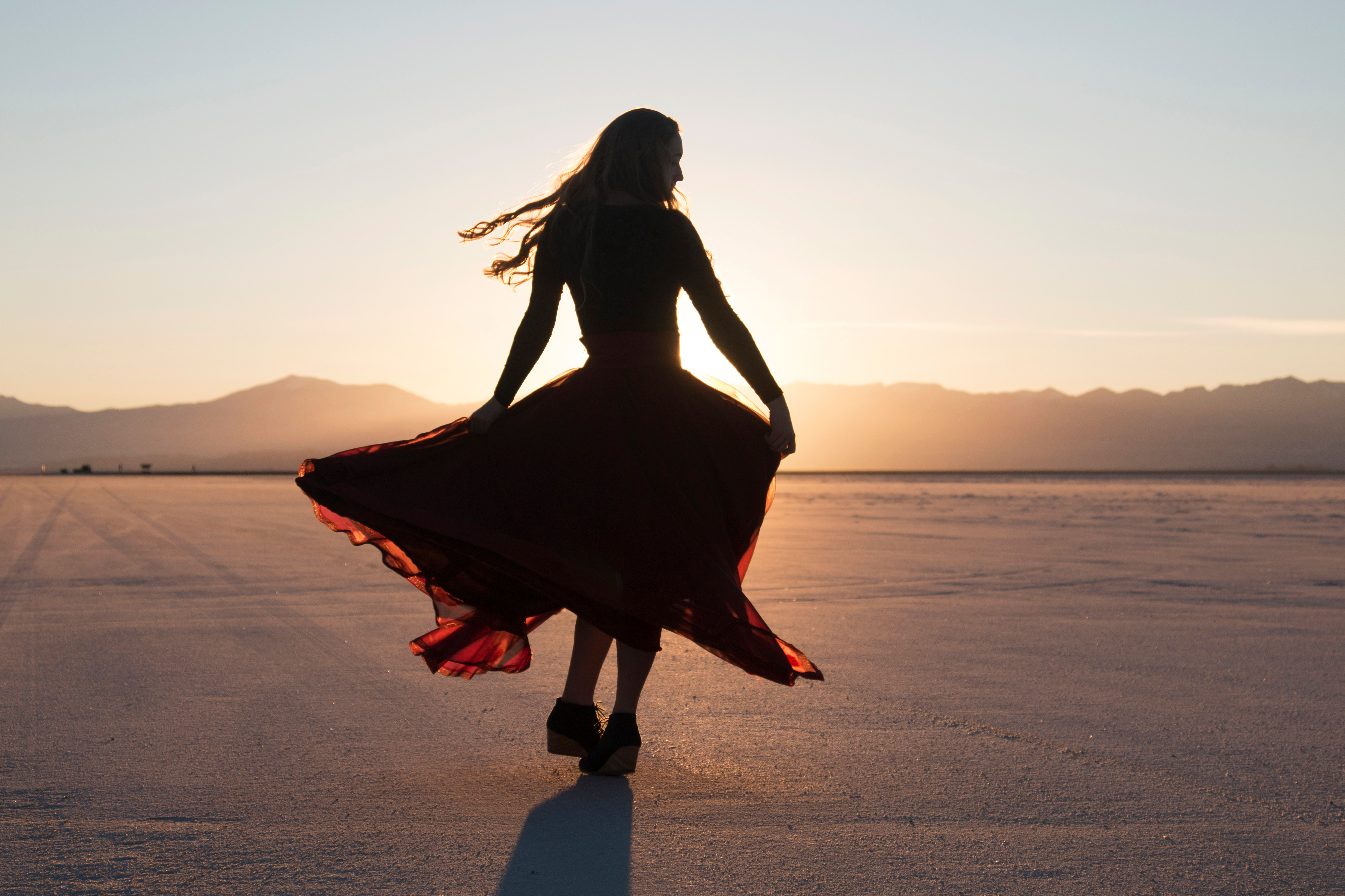 silhouette of a lady in red twirling in the desert