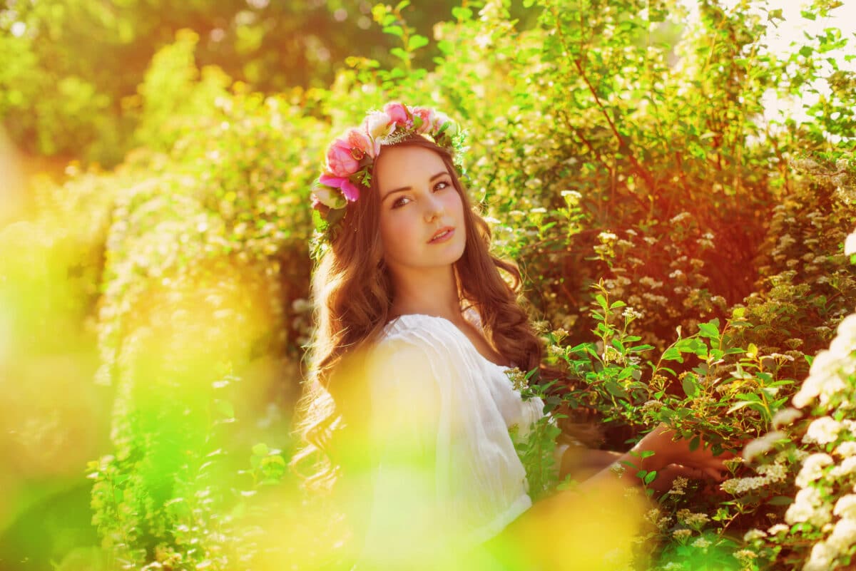 beautiful lady with long hair in floral wreath in the spring garden