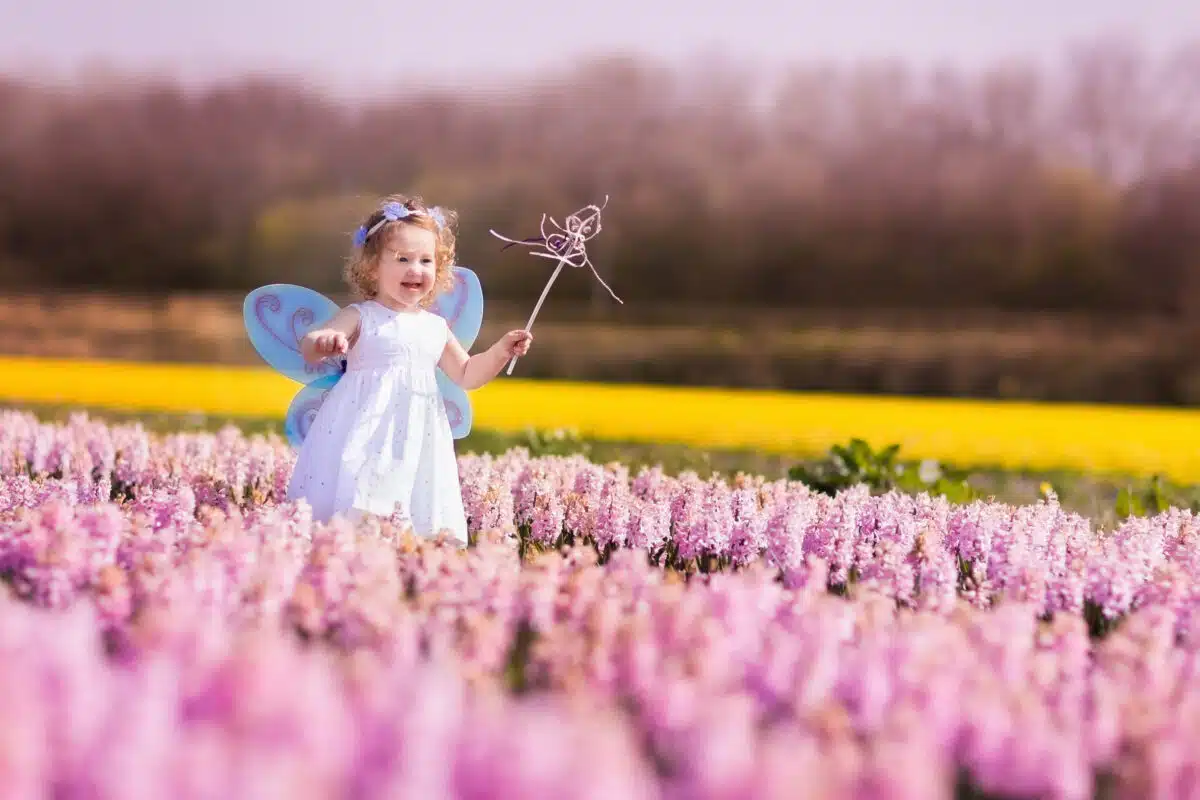 Little girl fairy playing in a hyacinth field