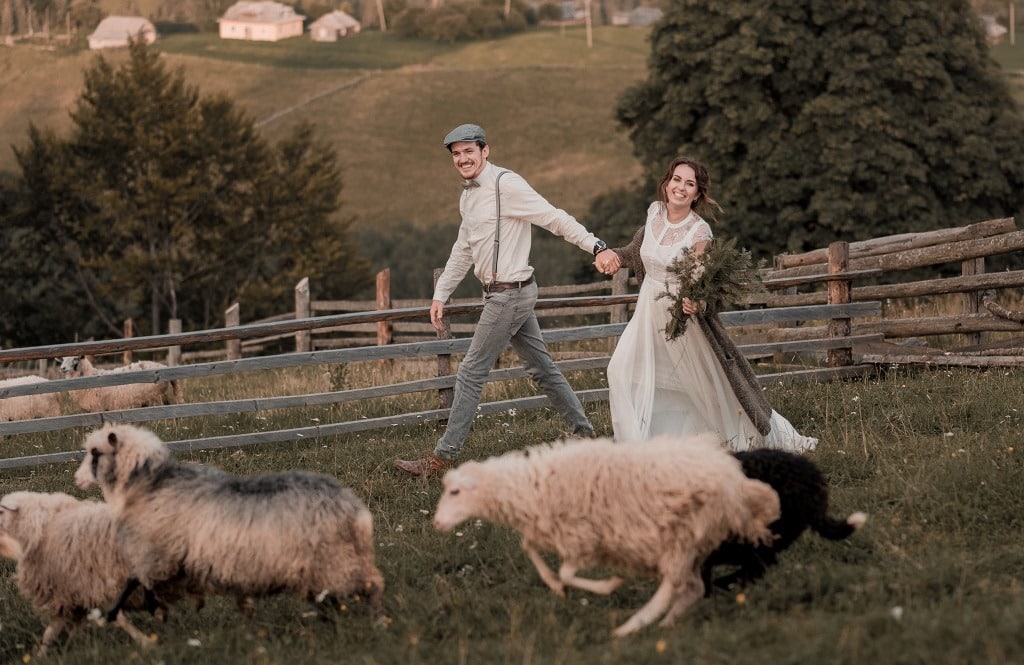 Vintage bride and groom on a ranch with a horse and sheep on a hill.
