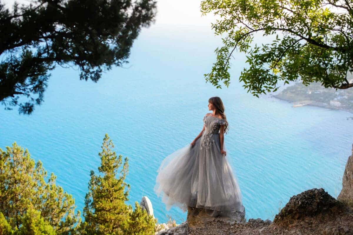 beautiful princess stands on the edge of a mountain with view of the blue ocean