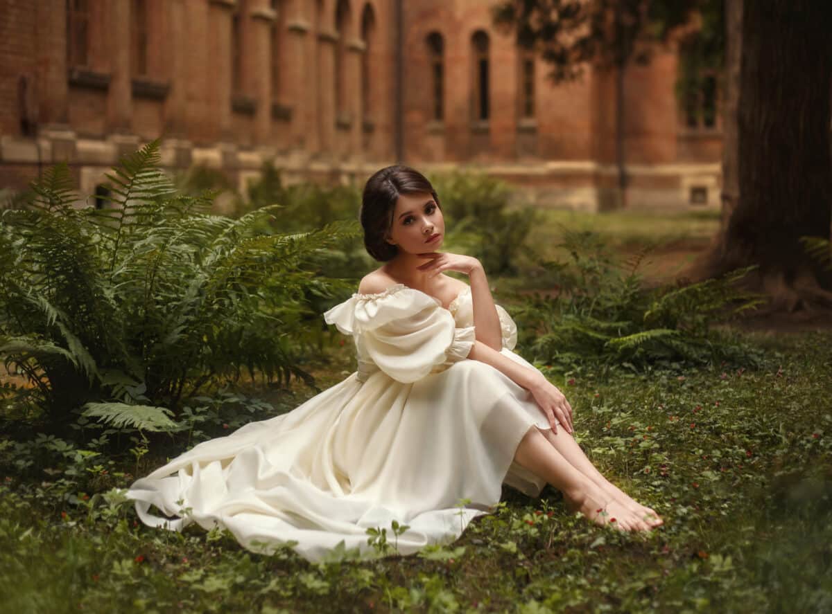 An incredibly beautiful princess sits in the castle garden amid the fern and moss. A beautifully childish face and collected hair is a neat hairdo. On the lady is a vintage ivory dress. Artistic Photo