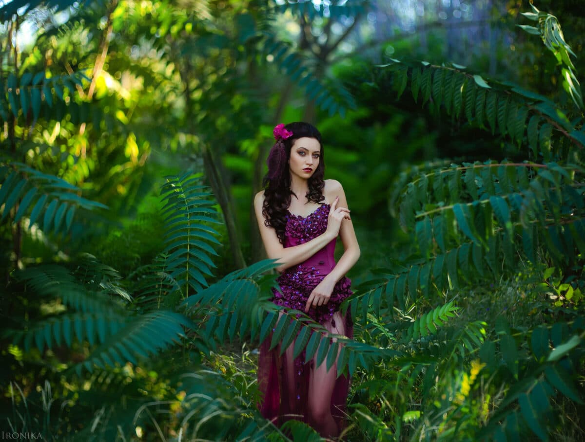 beautiful girl in a red dress standing in the thickets of the jungle, an unusual make-up, fashionable toning